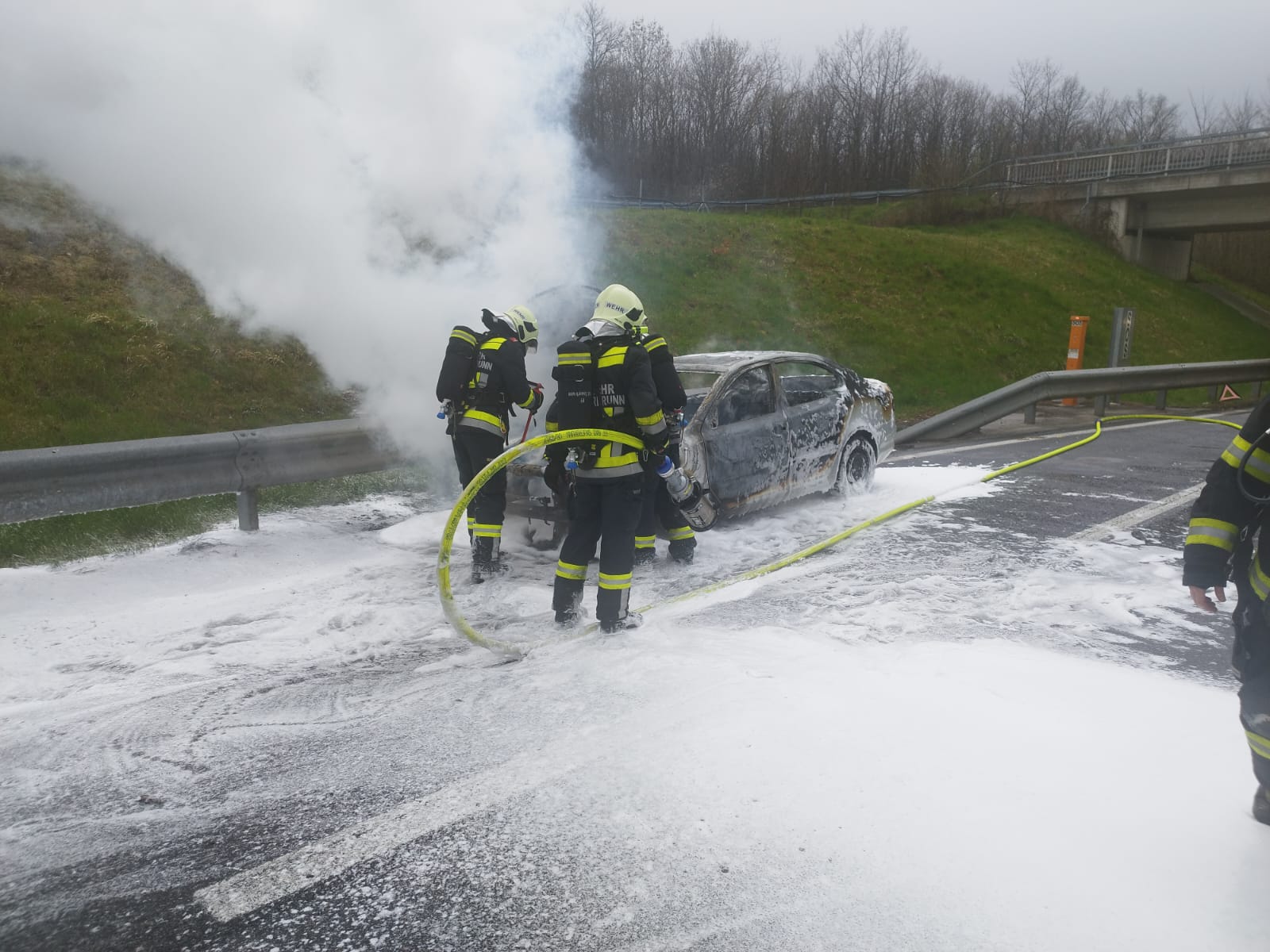 Feuerwehrkräfte bei der Brandbekämpfung an einem Fahrzeug